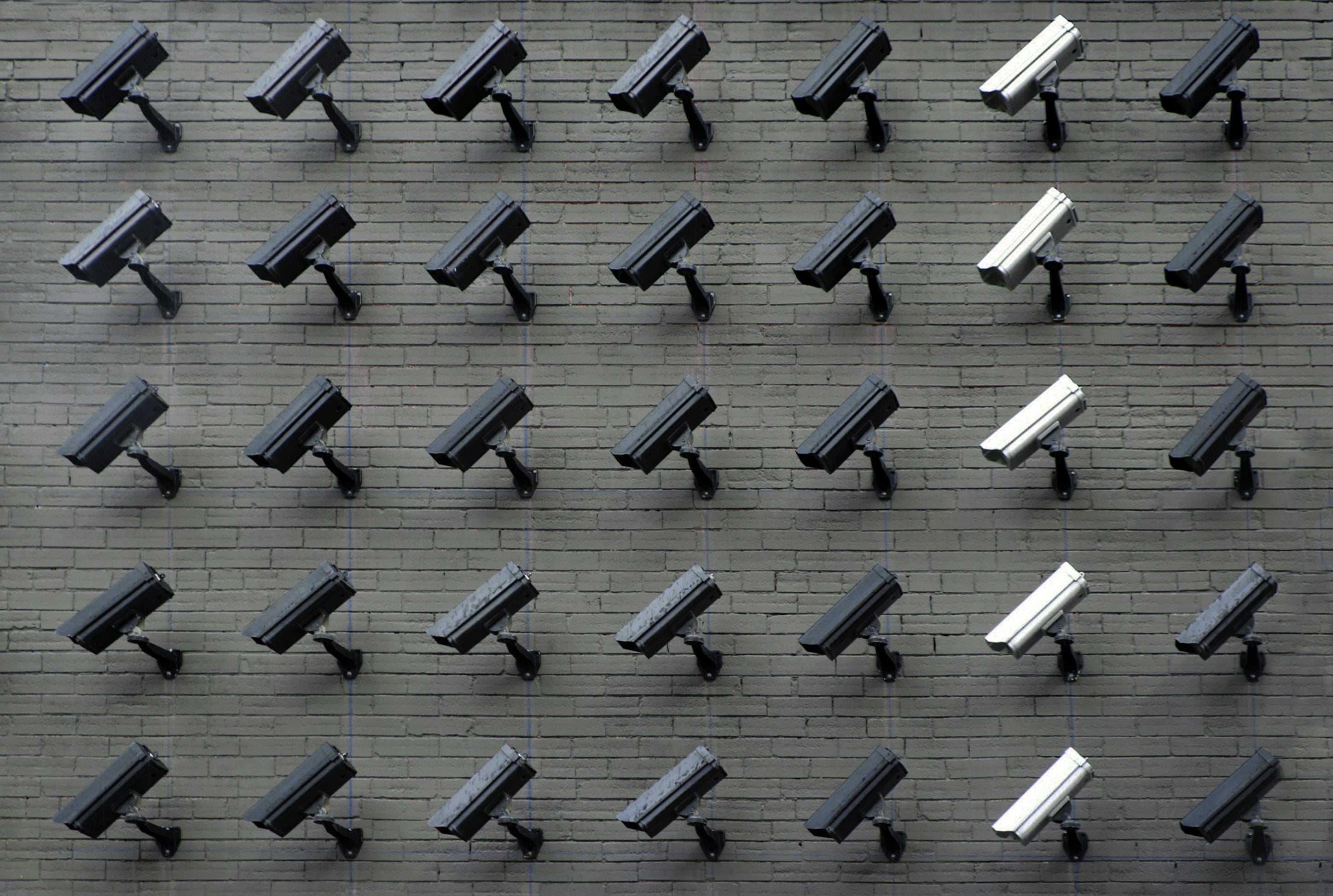 A brick wall of surveillance cameras arranged in an aesthetically perfect grid.