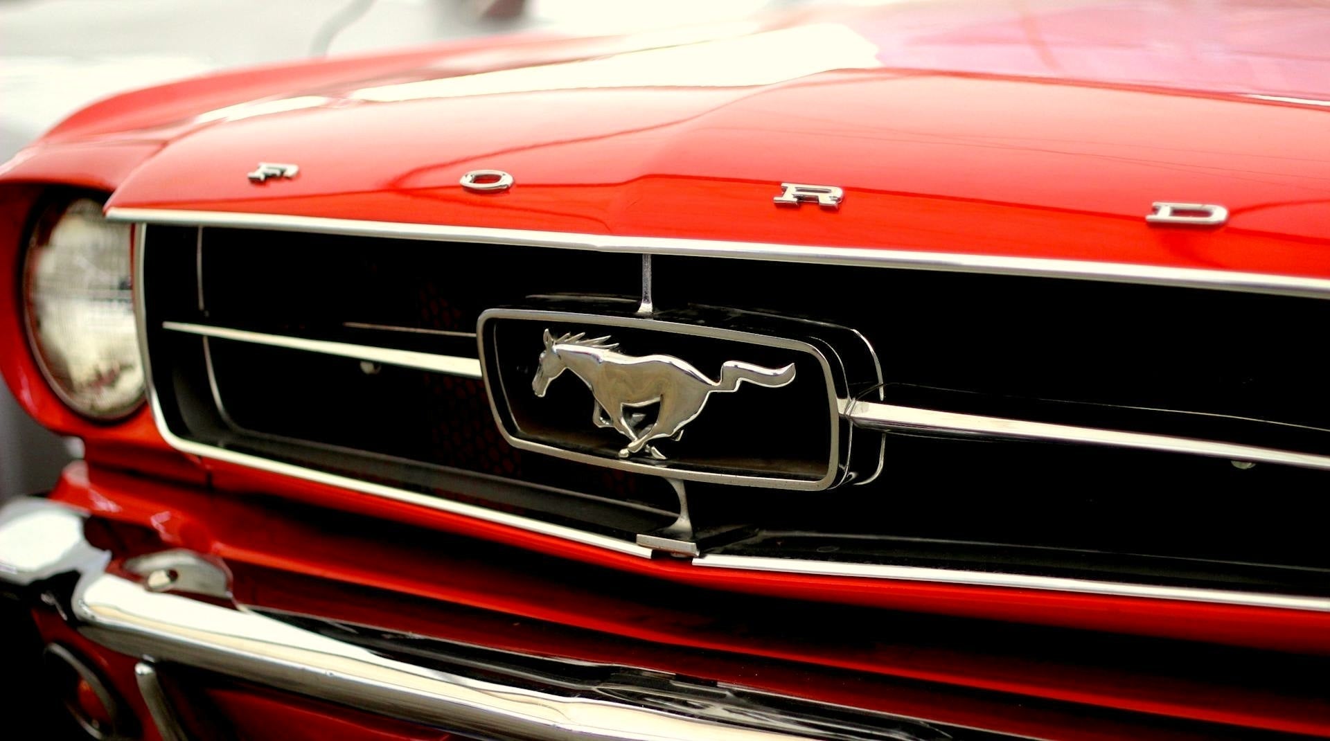 Close-up of red Ford Mustang grille with chrome pony emblem, symbolizing iconic vehicle protection