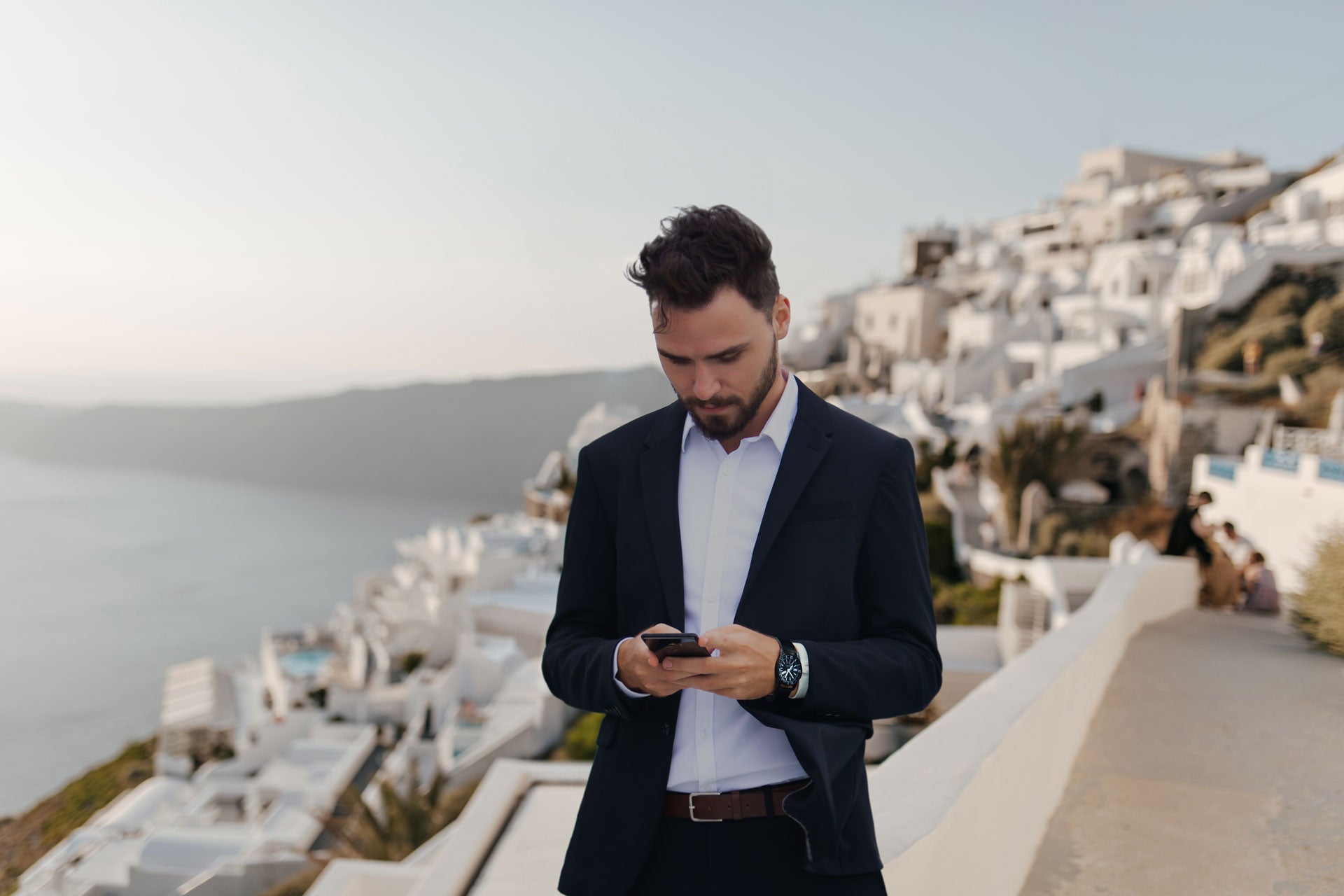 Man in Santorini, Greece, looking at the ASSURIoT app on his phone